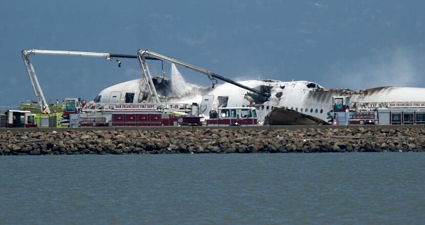 A fire truck sprays water on Asiana Flight 214 after it crashed at San Francisco...