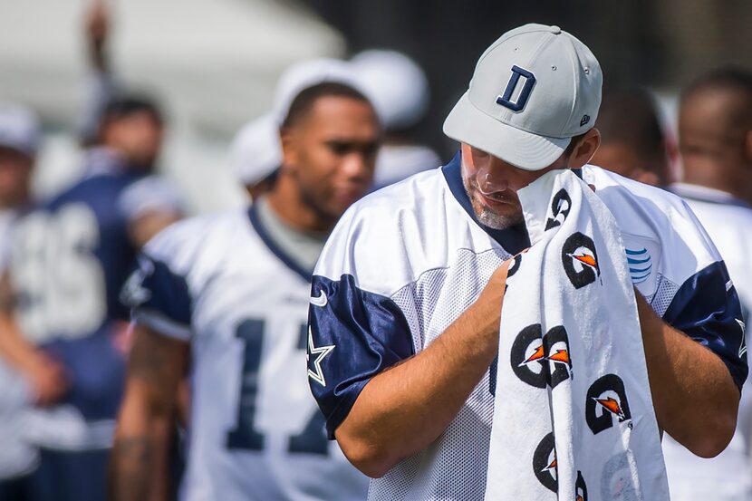 Dallas Cowboys quarterback Tony Romo wipes away sunscreen as he takes the field for the...