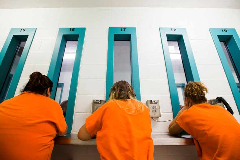 Female inmates talk to visitors through glass at Burnet County Jail in Burnet, Texas. The...