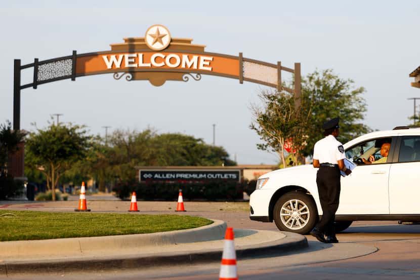 Security officials attend vehicles outside of the north entrance of Allen Premium Outlets...
