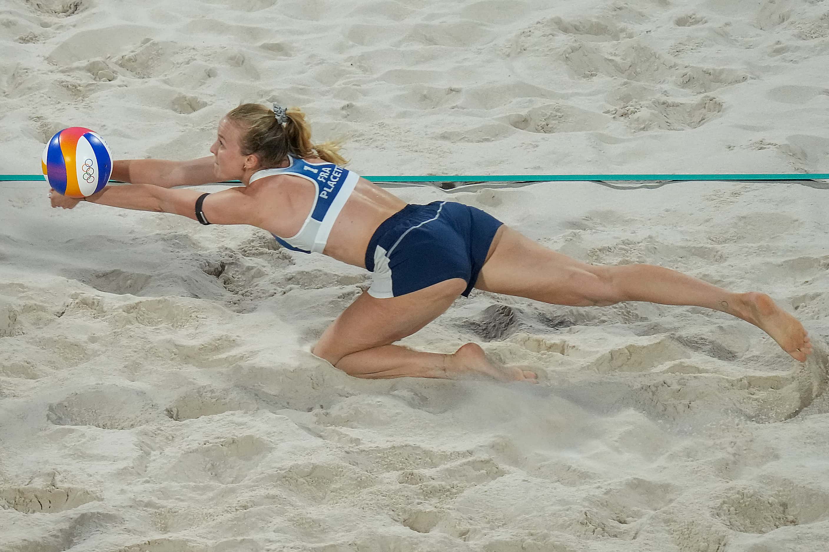 Lezana Placette of France dives for the ball against Germany during women’s beach volleyball...