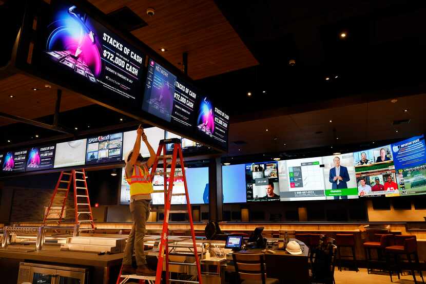 A worker put the finishing touches on a bank of video screens having over The League casino...