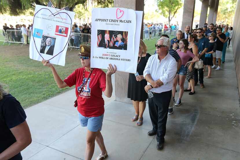 Cindy O'Neil of Tucson, Arizona held up signs as she and others waited in line for the...