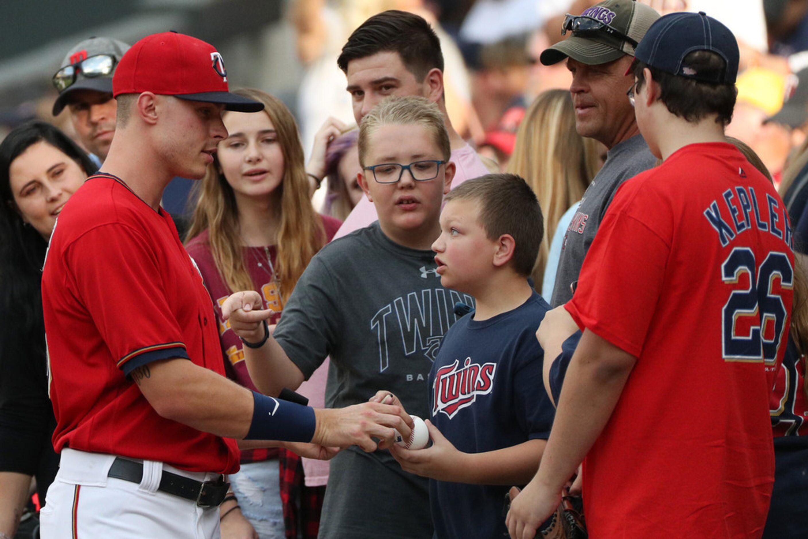 Minnesota Twins right fielder Max Kepler, left, signs autographs with fans prior to the...