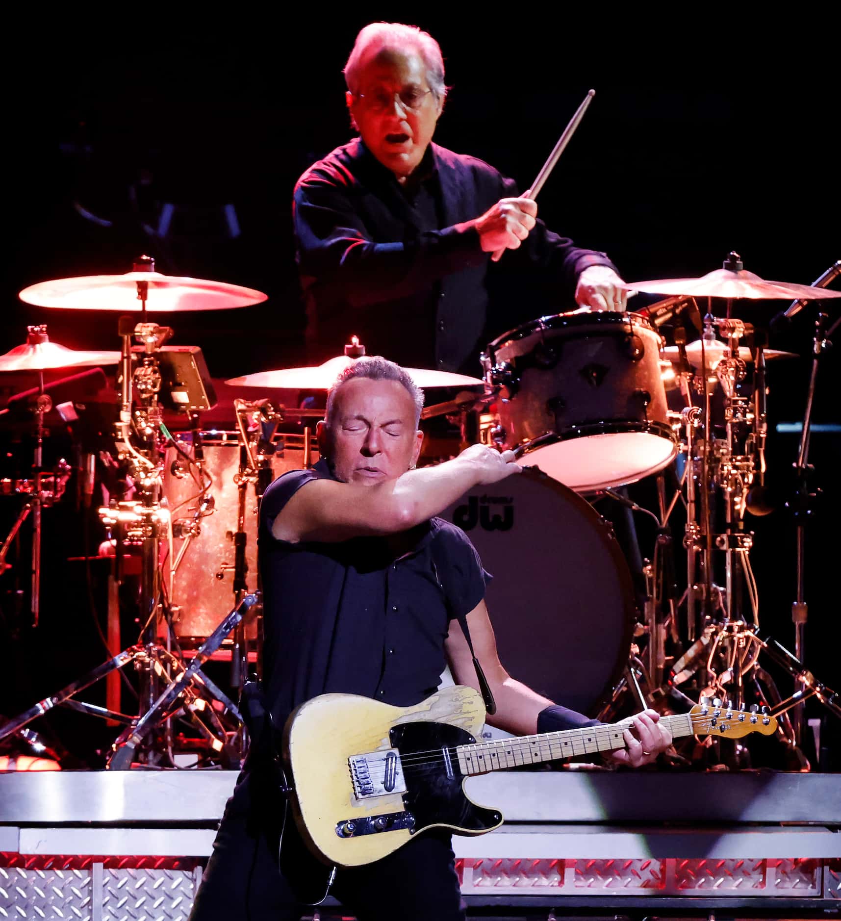 Clad in a black pearl snap shirt and black pants, Bruce Springsteen performs with drummer...