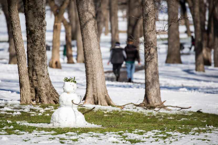 Grass starts to be exposed around a snowman in Tenison Park as warmer afternoon temperatures...