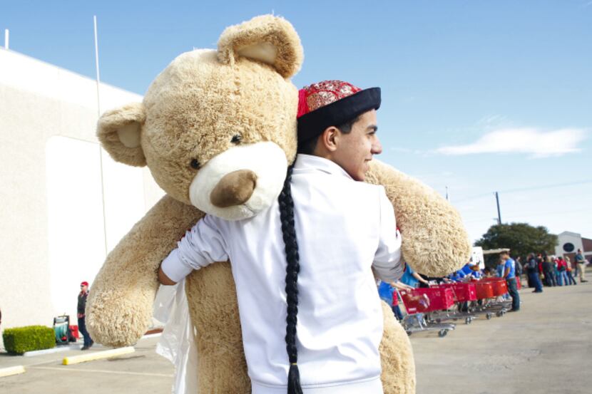 Eyad Alrabbat carried an oversized teddy bear to the toy donation collection room for the...