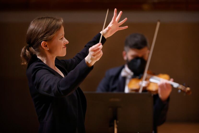 Assistant conductor Katharina Wincor leads violinist Nathan Olson (right) and the rest of...