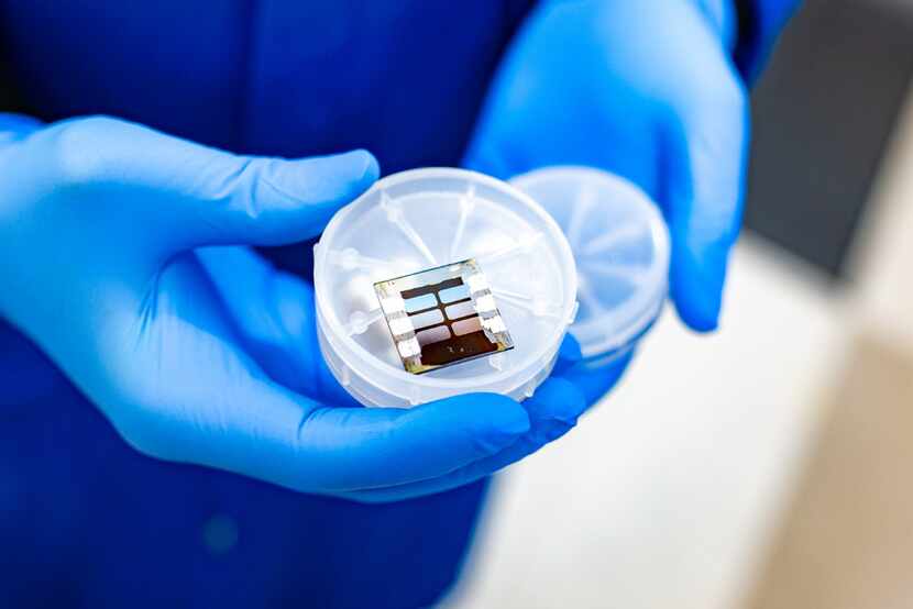 A UT Dallas researcher holds a piece of a solar panel that was produced using a heating...