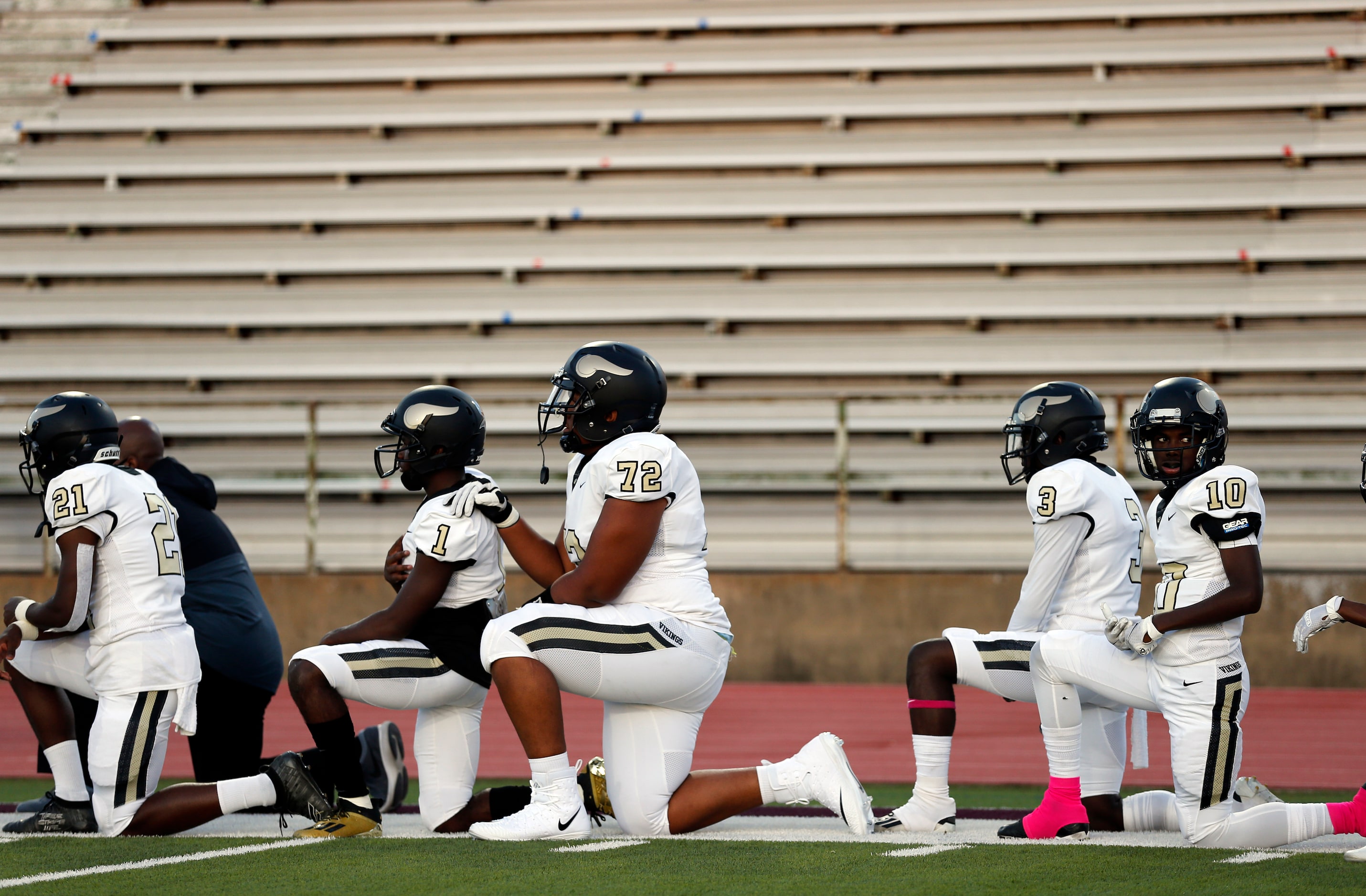 Pinkston football players Dominic Eldridge (72) and Bronya Todd (1) and others take a knee...