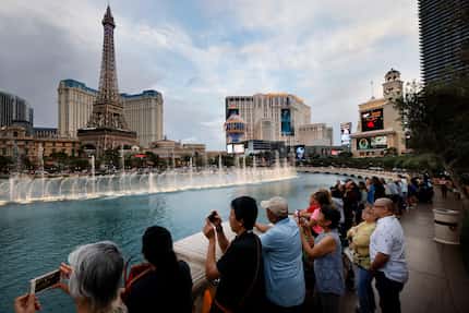 Tourists watch the dancing water feature at Bellagio Fountain along the Las Vegas strip...