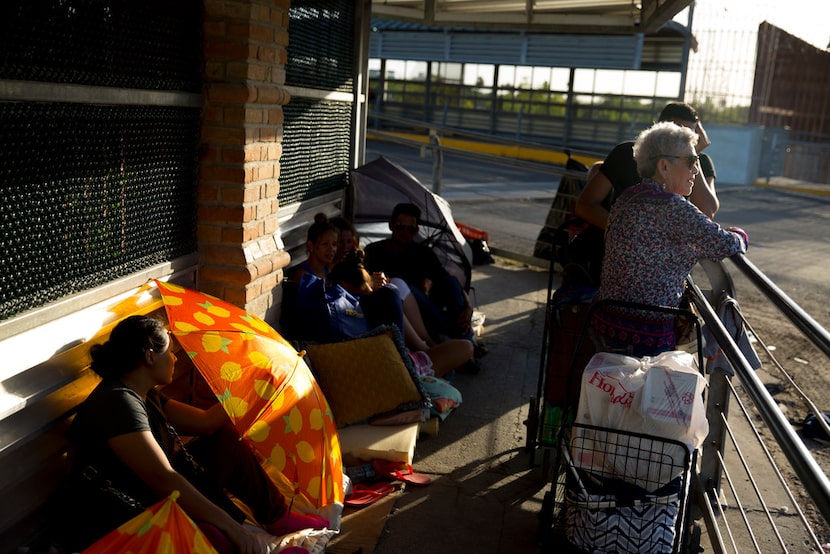 Immigrants wait to be processed on the U.S. side of the international bridge in between...