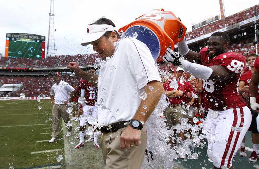 Oklahoma Sooners head coach Bob Stoops is doused with an iced water cooler by defensive end...
