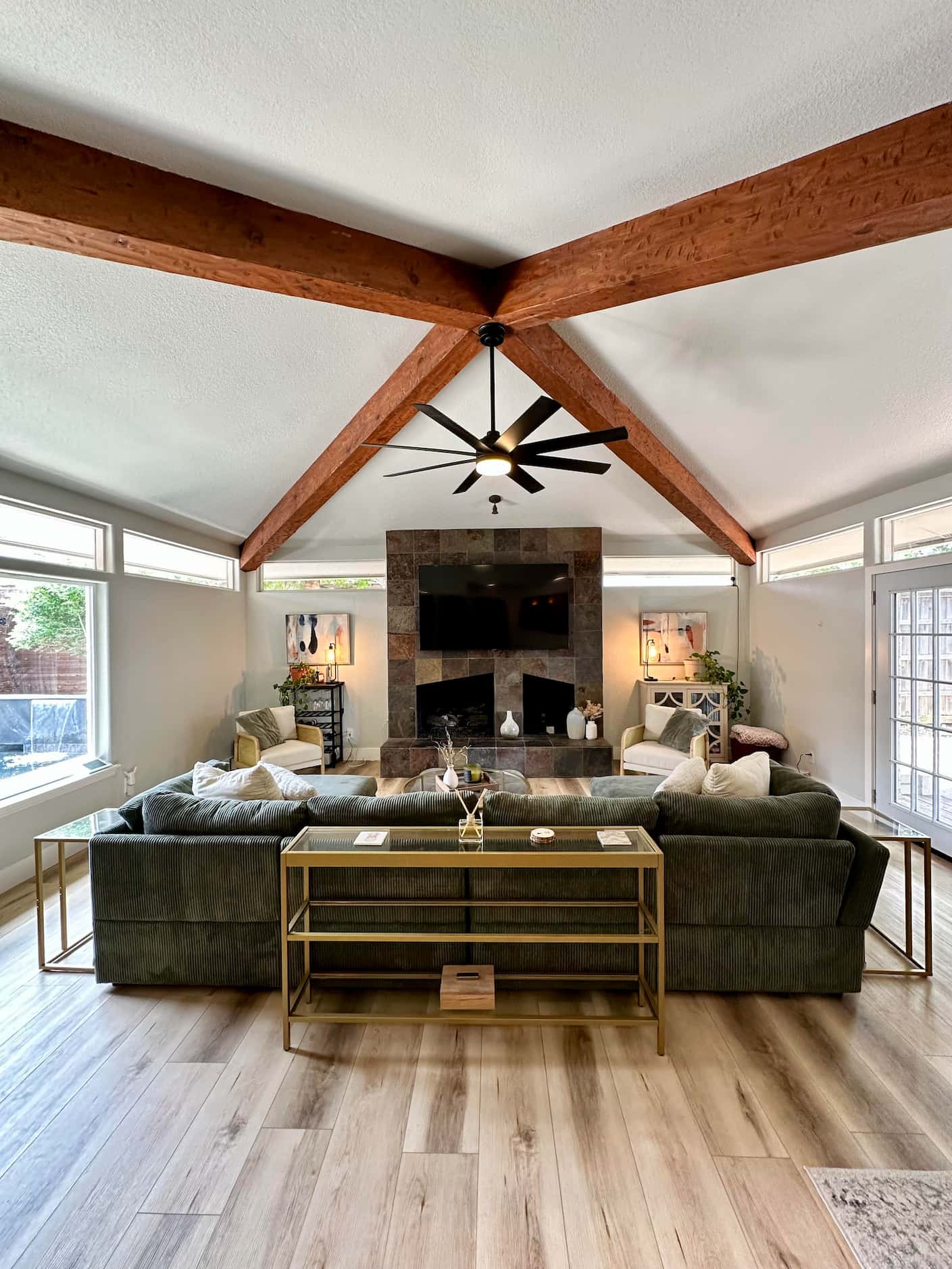 Living room with vaulted ceiling, beam accents on the ceiling and stone fireplace surround