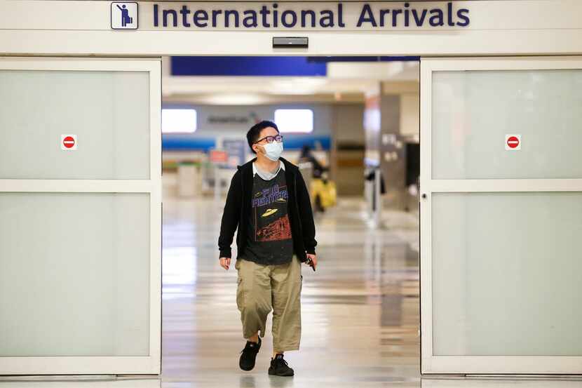 Wearing a protective mask, Frank Ye, of Shenzhen, China, arrives in the international...