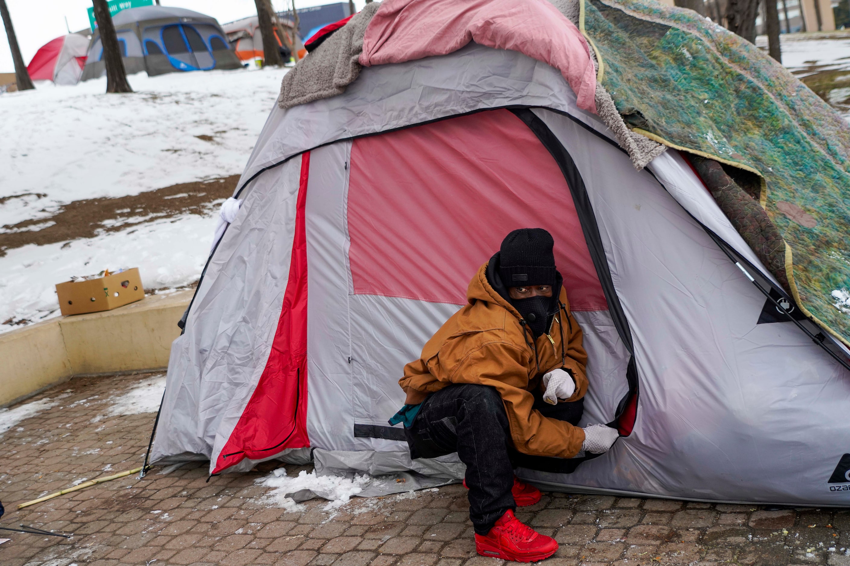 Carlos Jackson zips up the tent he is living in with two other homeless men at Forest Lane...