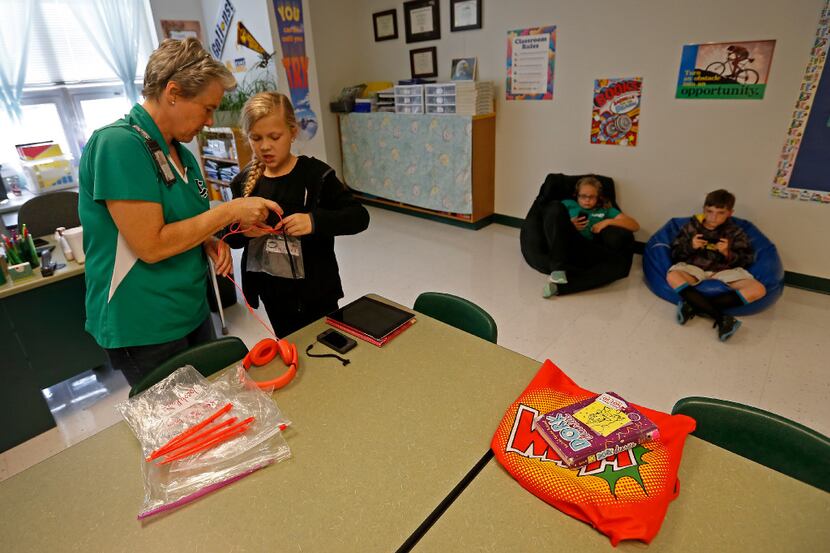 Teacher Leslie Patterson helps her fourth-grade student Kaelynne Norlie check out an iPod to...