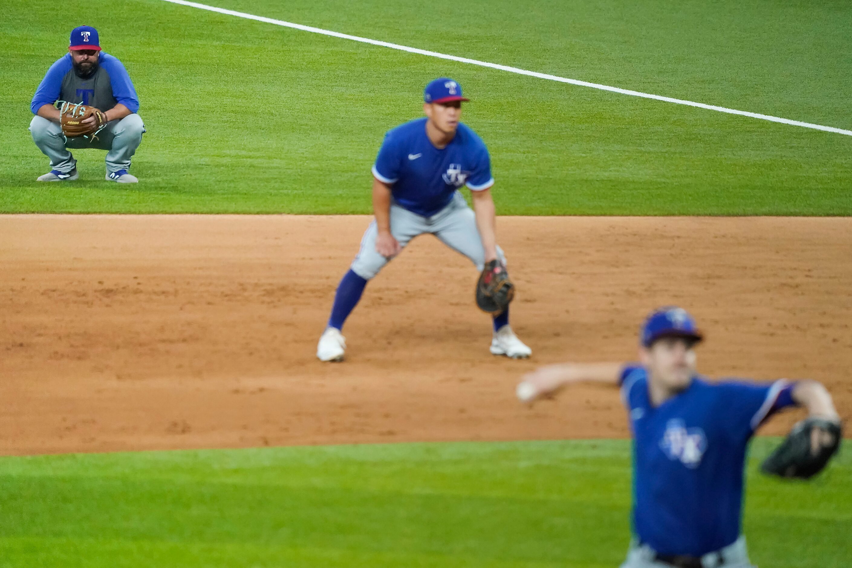 Texas Rangers infield coordinator Kenny Holmberg watches from the field as Jason Bahr...