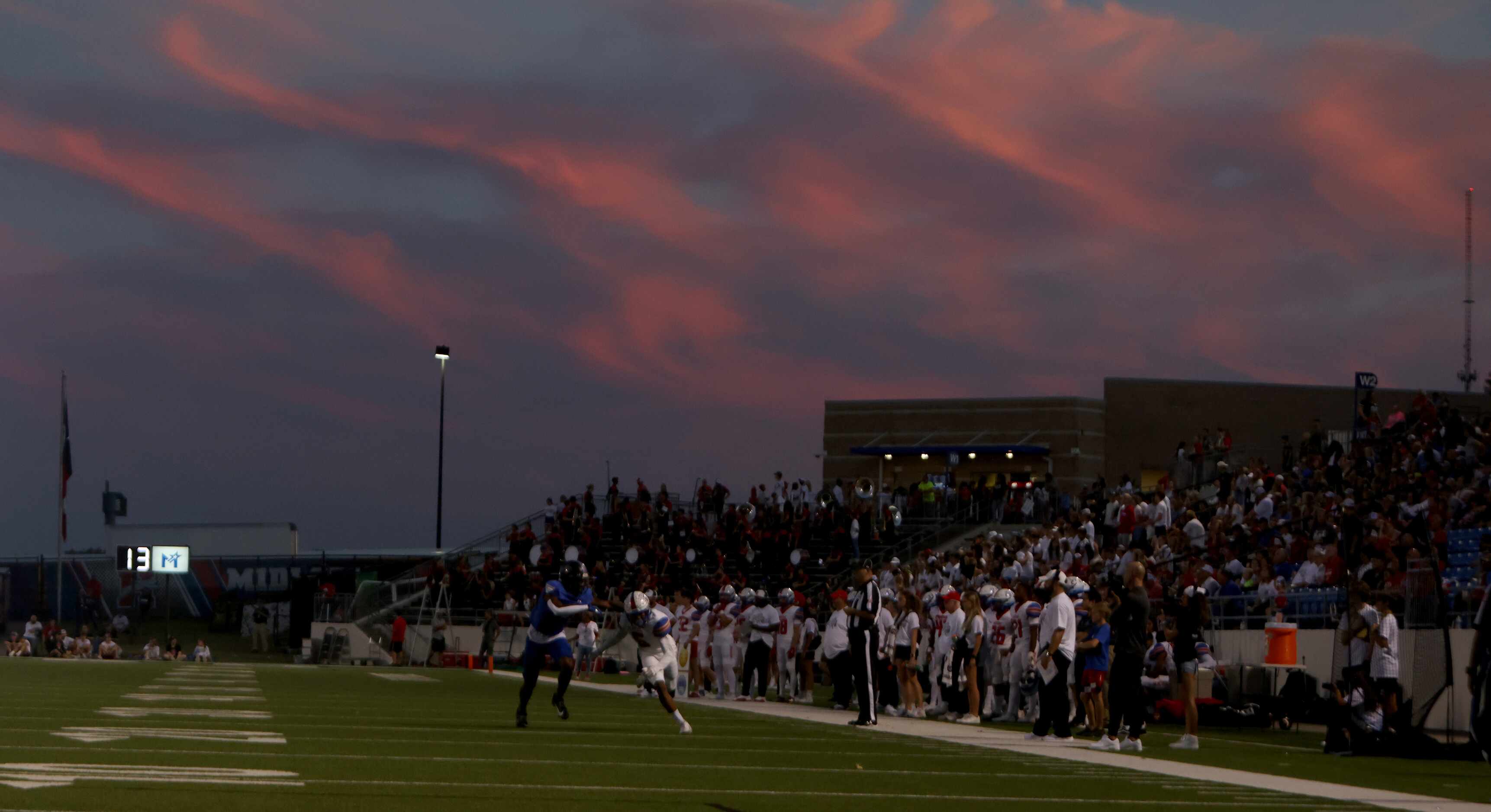 A colorful sunset serves as the backdrop to first quarter action of the Midlothian Heritage...