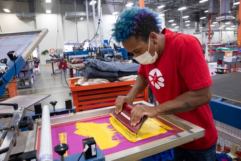 Manual screen printer Isaiah Gittens prepares a shirt at Custom Ink in Flower Mound.