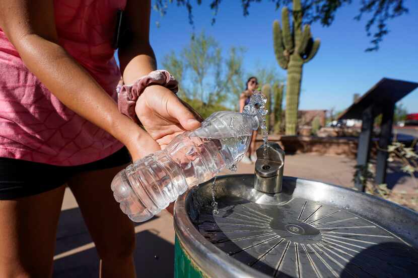 A hiker refills her water bottle before climbing Echo Canyon trail in Phoenix, Ariz,...