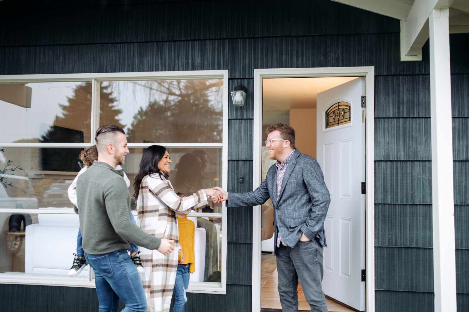 A Caucasian Real Estate Agent welcomes a multi-ethnic family to a viewing of a home they are...
