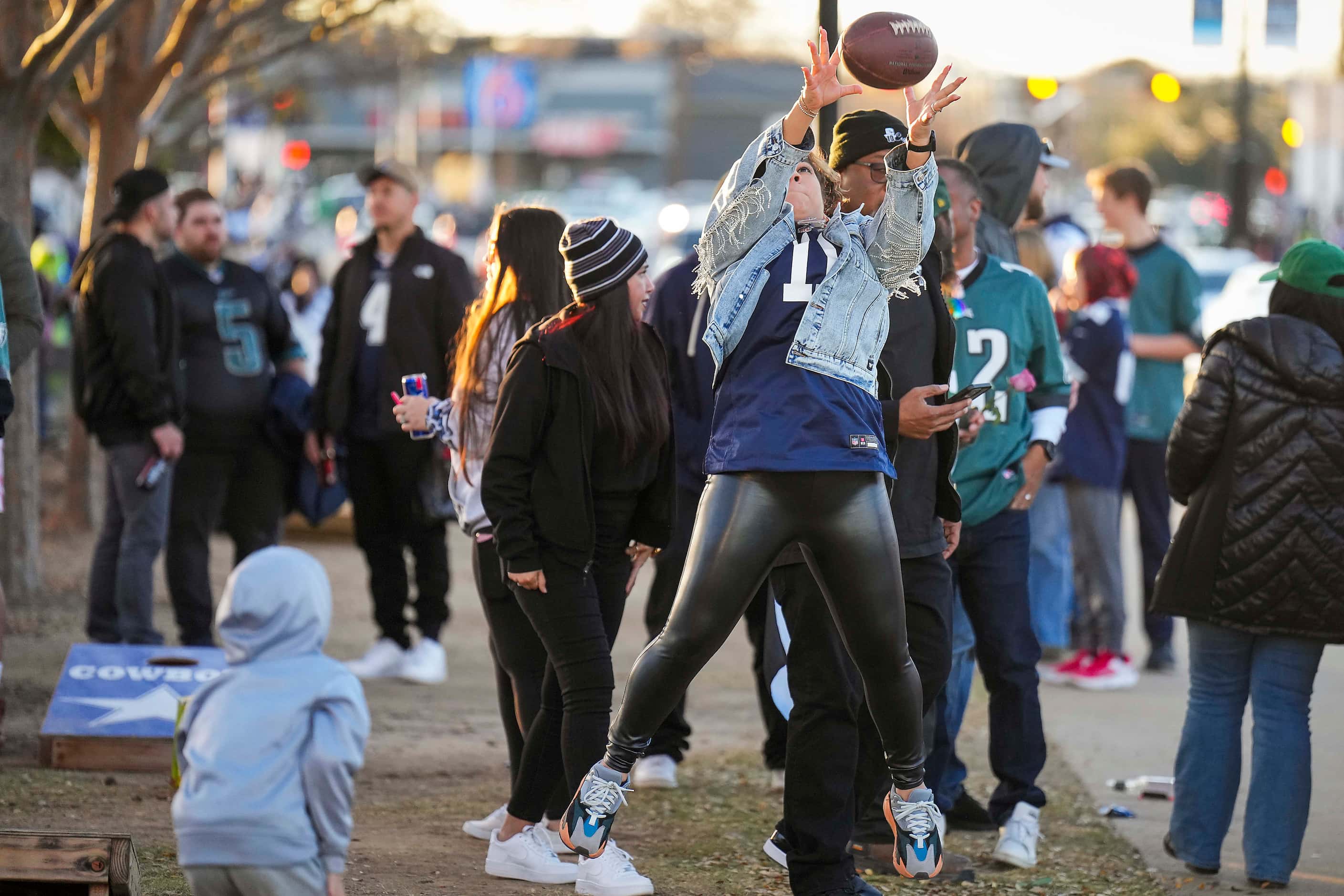 Fan Amy Zuaso catches a football while tailgating before an NFL football game between the...