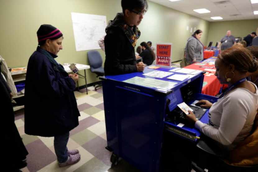 Unos votantes forman filas para que una funcionaria revise sus identidades de fotos en un...