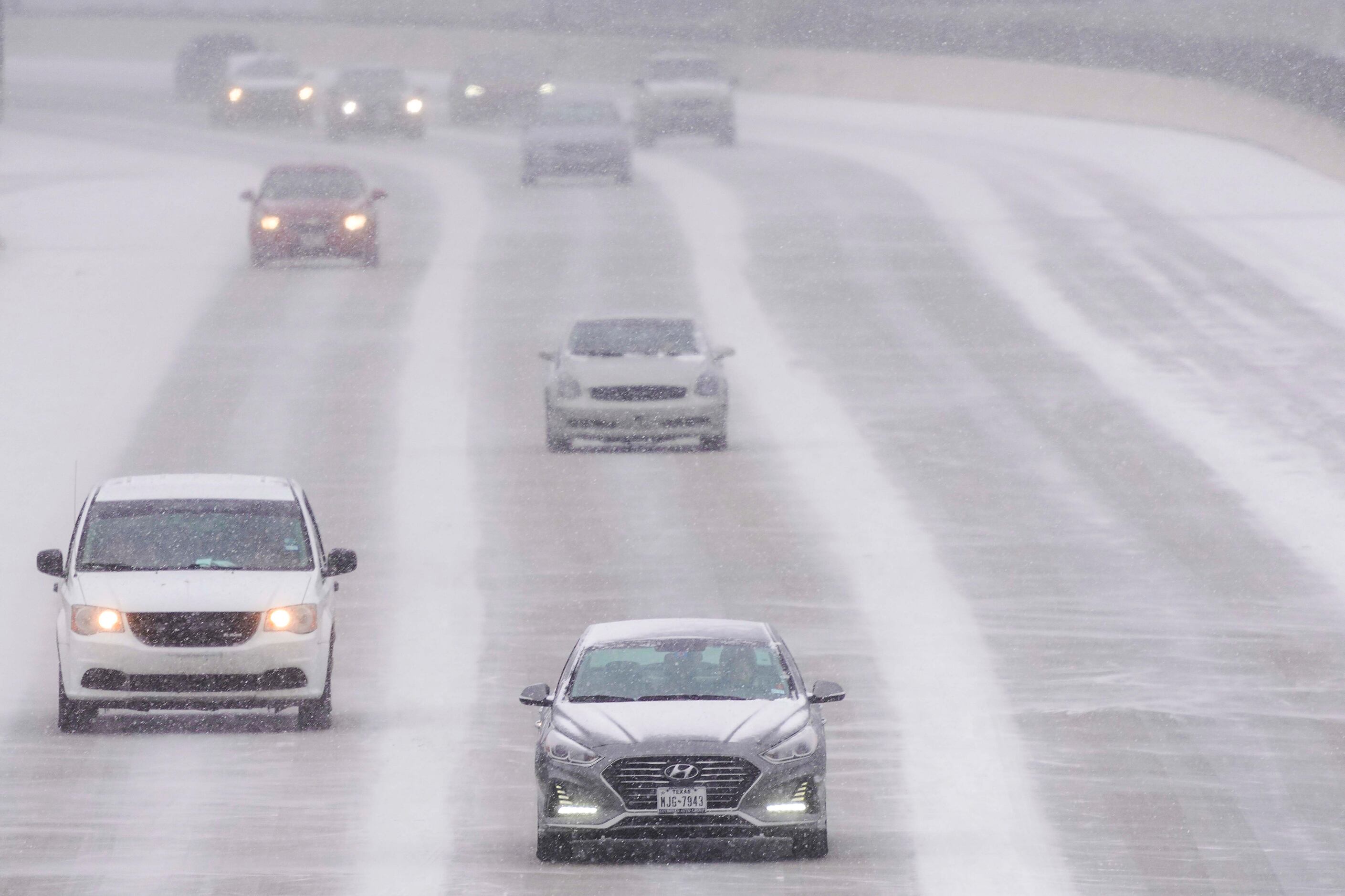 Traffic moves through snow on US-75 near the High Five interchange as a winter storm brings...