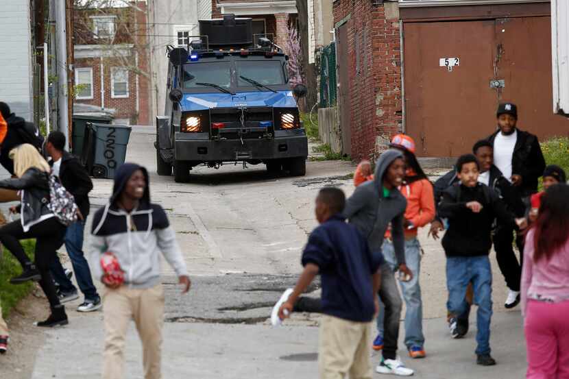 BALTIMORE, MD - APRIL 27:  A police vehicle drives down an alley toward protestors along...
