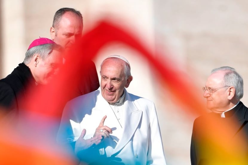 Pope Francis is pictured through colorful scarves waved by faithful at the end of a weekly...