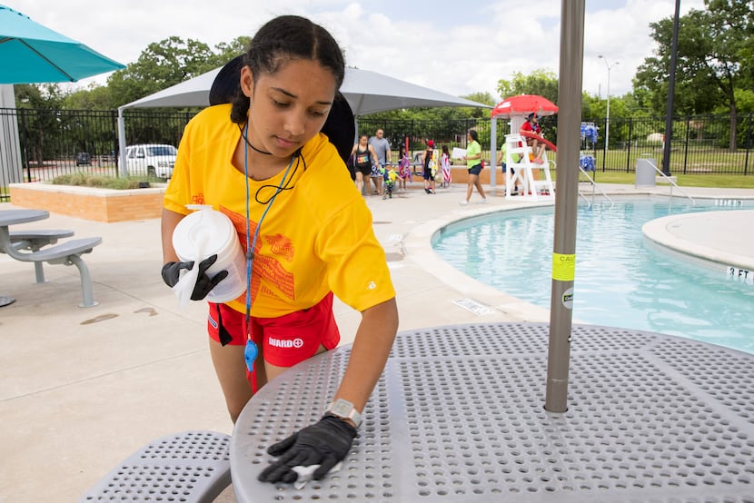 Lifeguard Jaedan Freeman, 17, wipes down tables with disinfectant wipes during a break at...