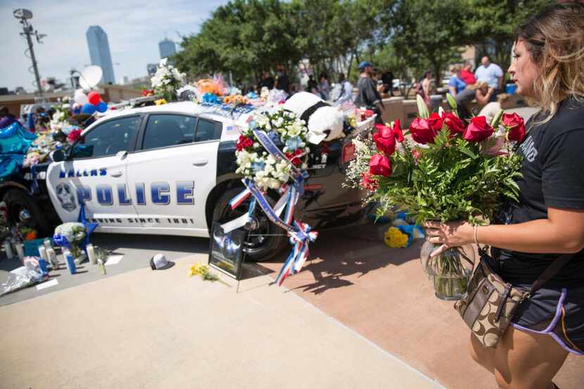 A woman placed flowers at a memorial outside the Dallas police headquarters on July 8, the...