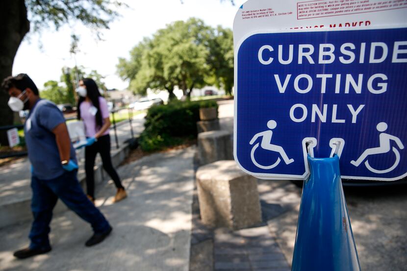 High school poll workers Sebastian Roman (left), 18, and Diana Paulin, 18, work a curbside...