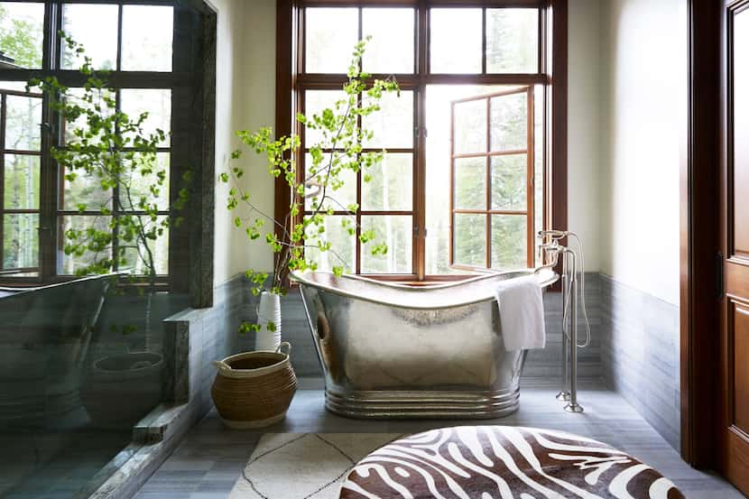 Primary bathroom with large windows, silver freestanding tub and an animal-print ottoman