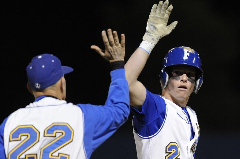 Frisco's Jordan Goudie gets a high five from his coach Scott Cook after a triple in the...