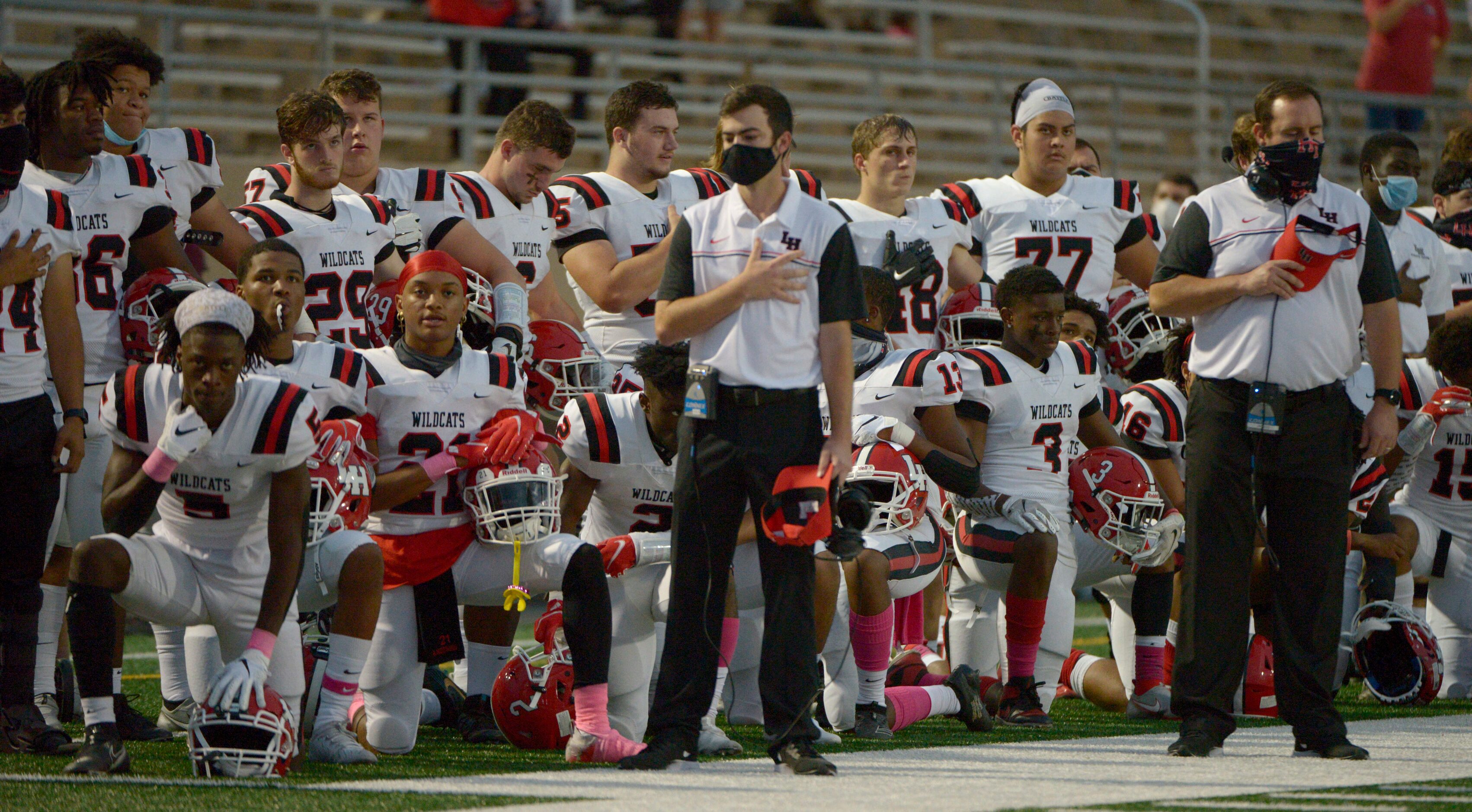 Lake Highland players and coaches during the National Anthem before a high school football...