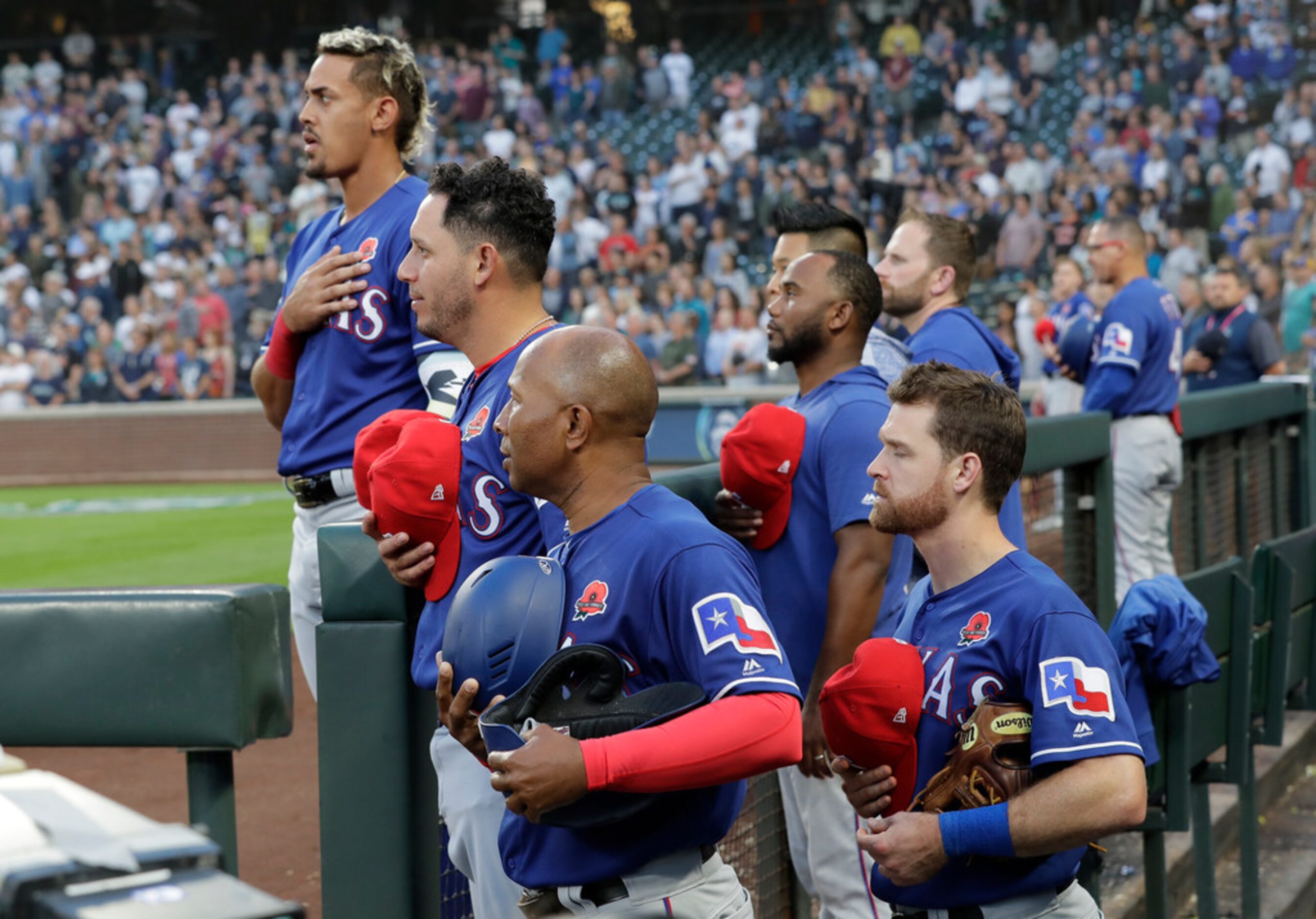 Texas Rangers players and coaches stand in the dugout during the singing of "God Bless...