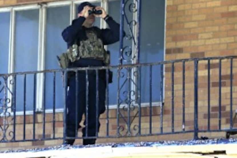  A police officer uses binoculars across from the Muhammad Mosque to monitor the situation....
