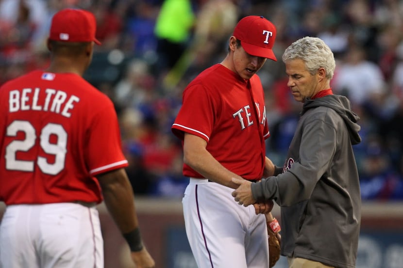 Texas Rangers trainer Jamie Reed checks the wrist of Texas Rangers starting pitcher Nick...