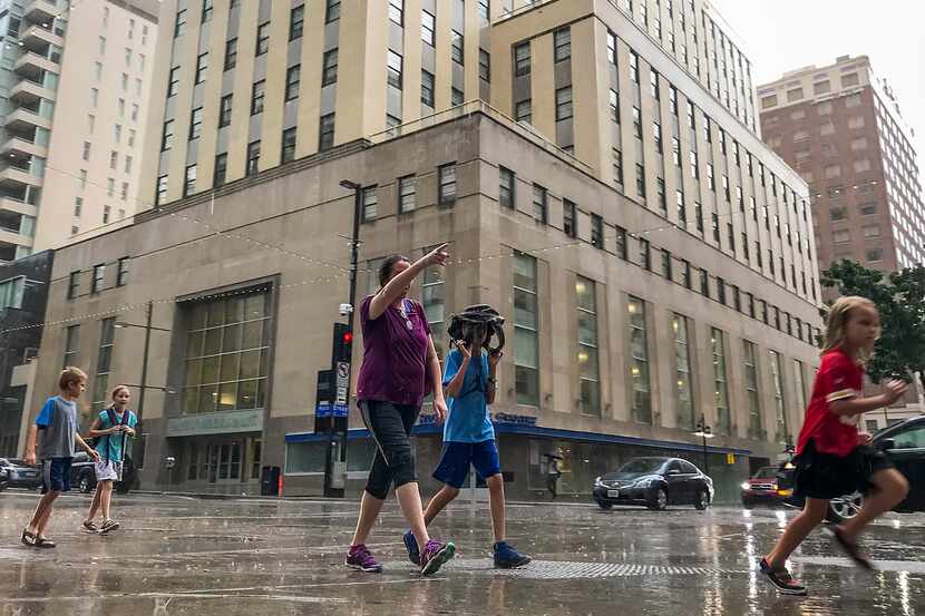 Pedestrians try to take cover from the rain as a thunderstorm rolled through downtown Dallas...