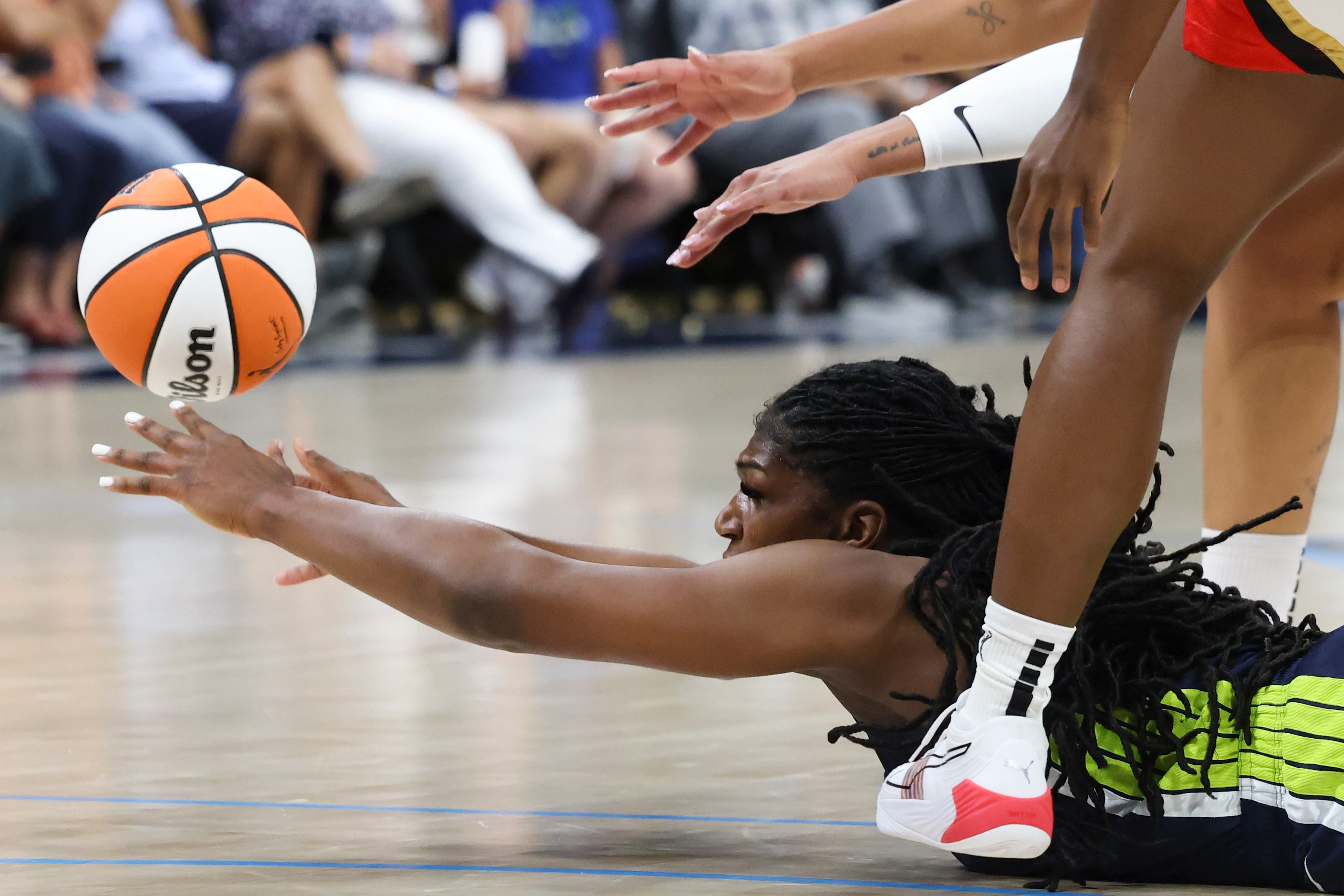 Dallas Wings center Teaira McCowan (7) passes the ball to a teammate while sprawled across...