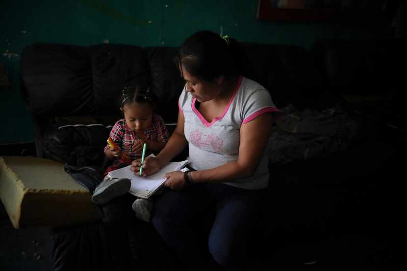 Lucia, 38, from Guerrero state, draws with her youngest daughter as she waits with her...