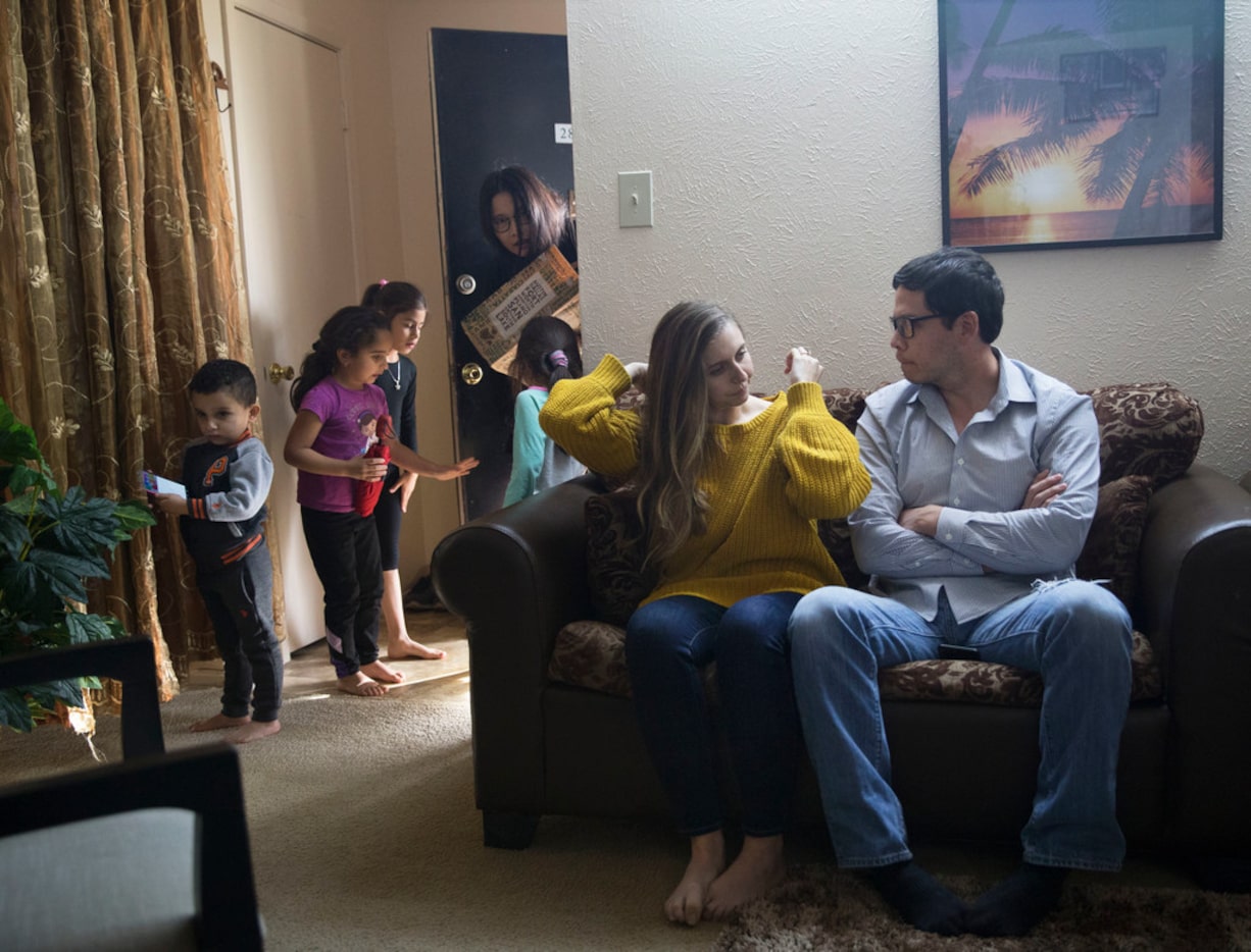 Lily Heine, left on couch, adjusts her hair beside Erick Espinoza, her fiance, as Break...