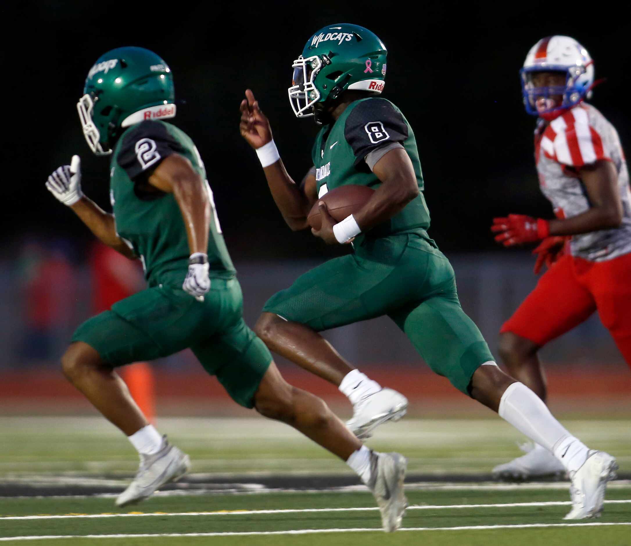 Kennedale quarterback Paul Donkor (8), center, rolls out of the backfield inside of running...