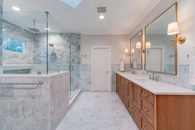 A primary bathroom has marble flooring and brass details.