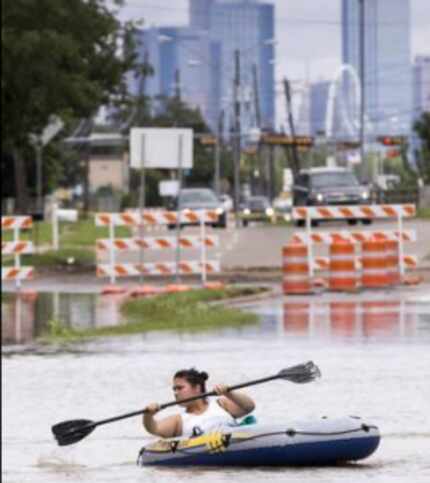  Beatrice Banda paddles a boat along a flooded section of Singleton Blvd. at Loop 12 on...