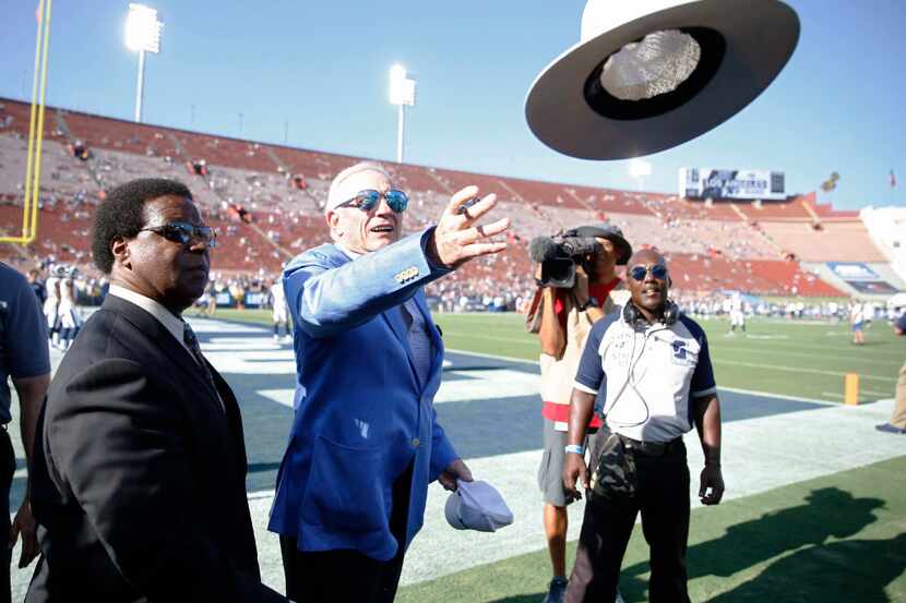 Dallas Cowboys owner and general manager Jerry Jones throws a hat back to a fan after...