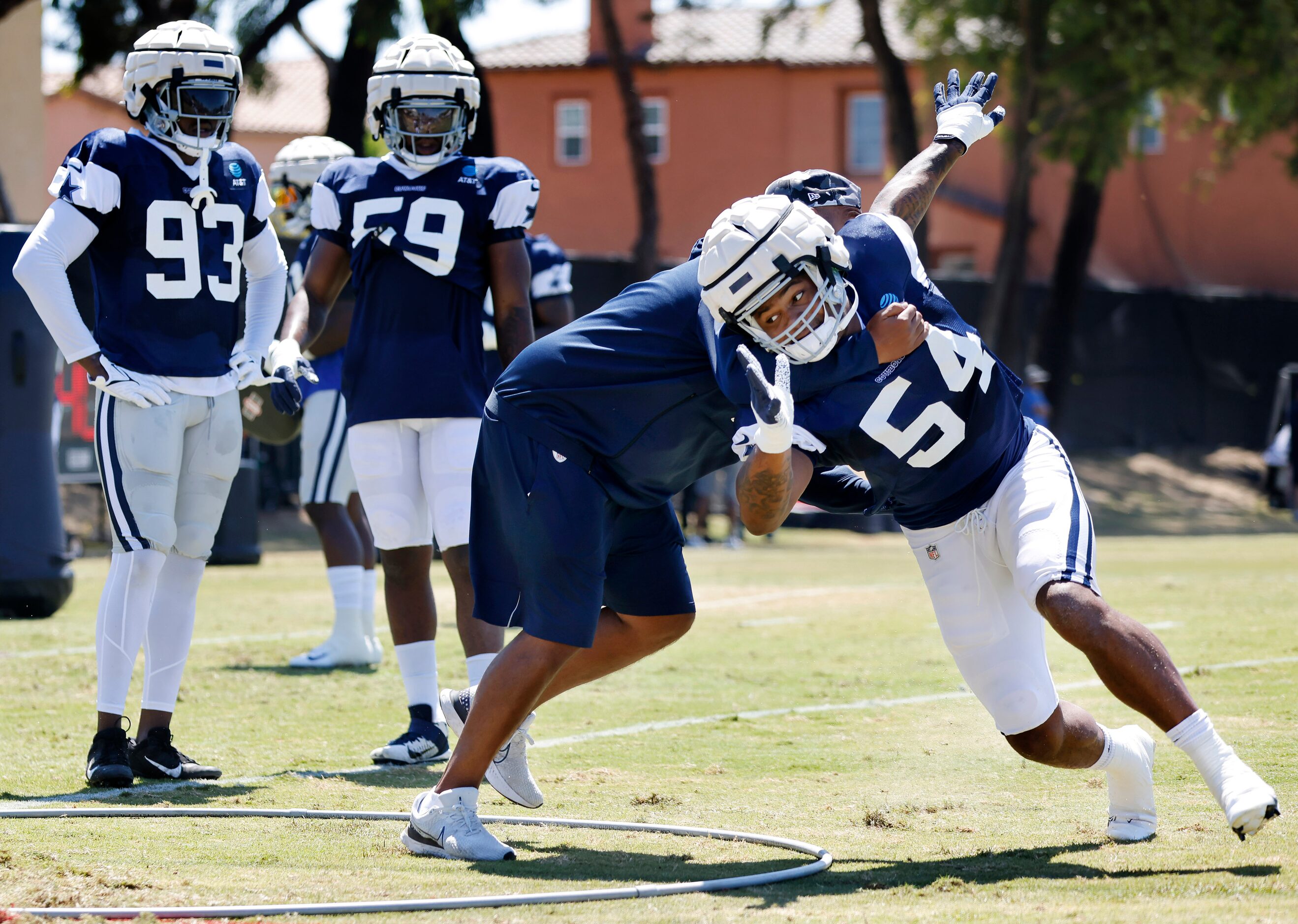 Dallas Cowboys defensive end Sam Williams (54) is fought off by defensive line coach Aden...