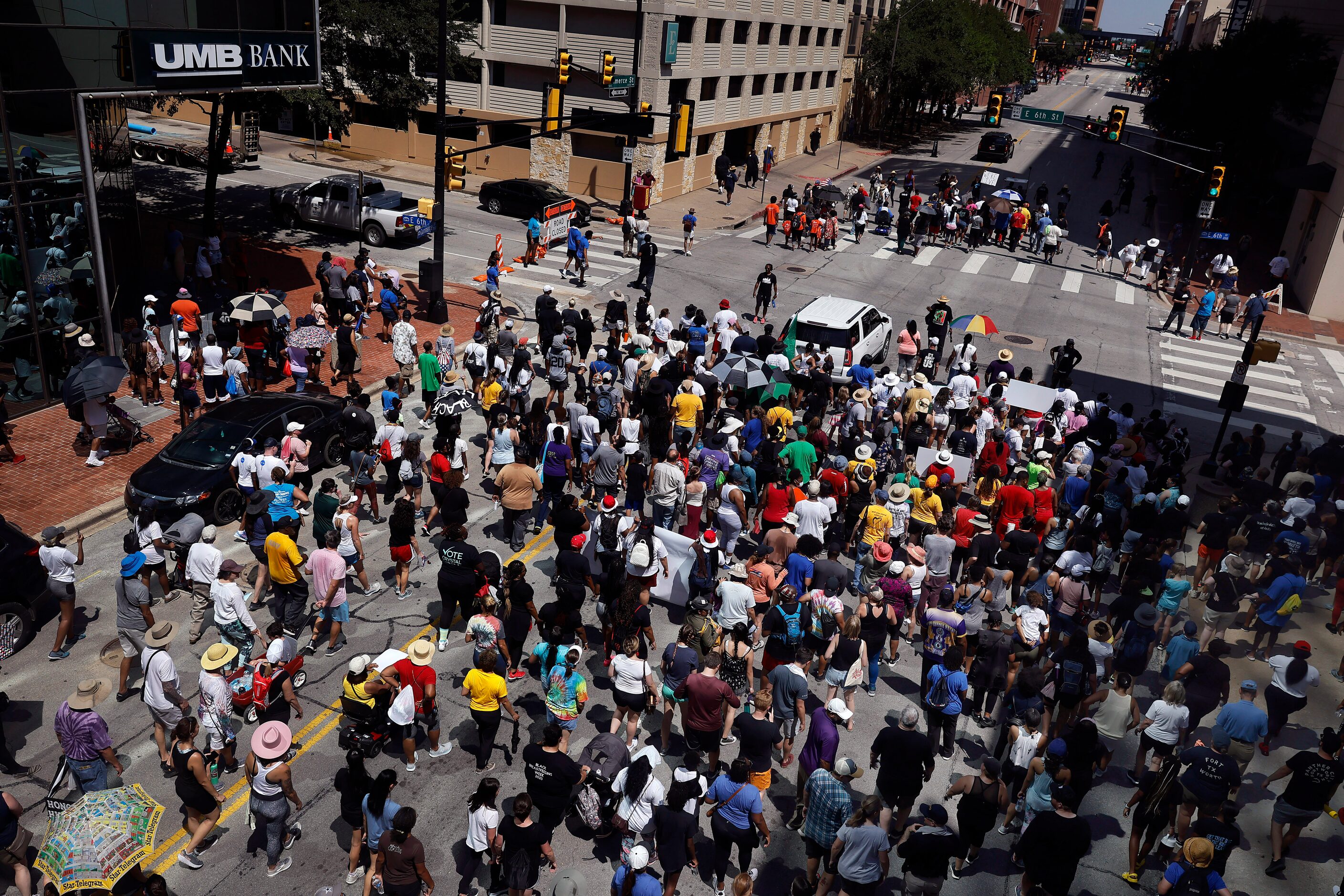 A large group of supporters follow Opal Lee (under umbrellas, top) down Commerce St. during...